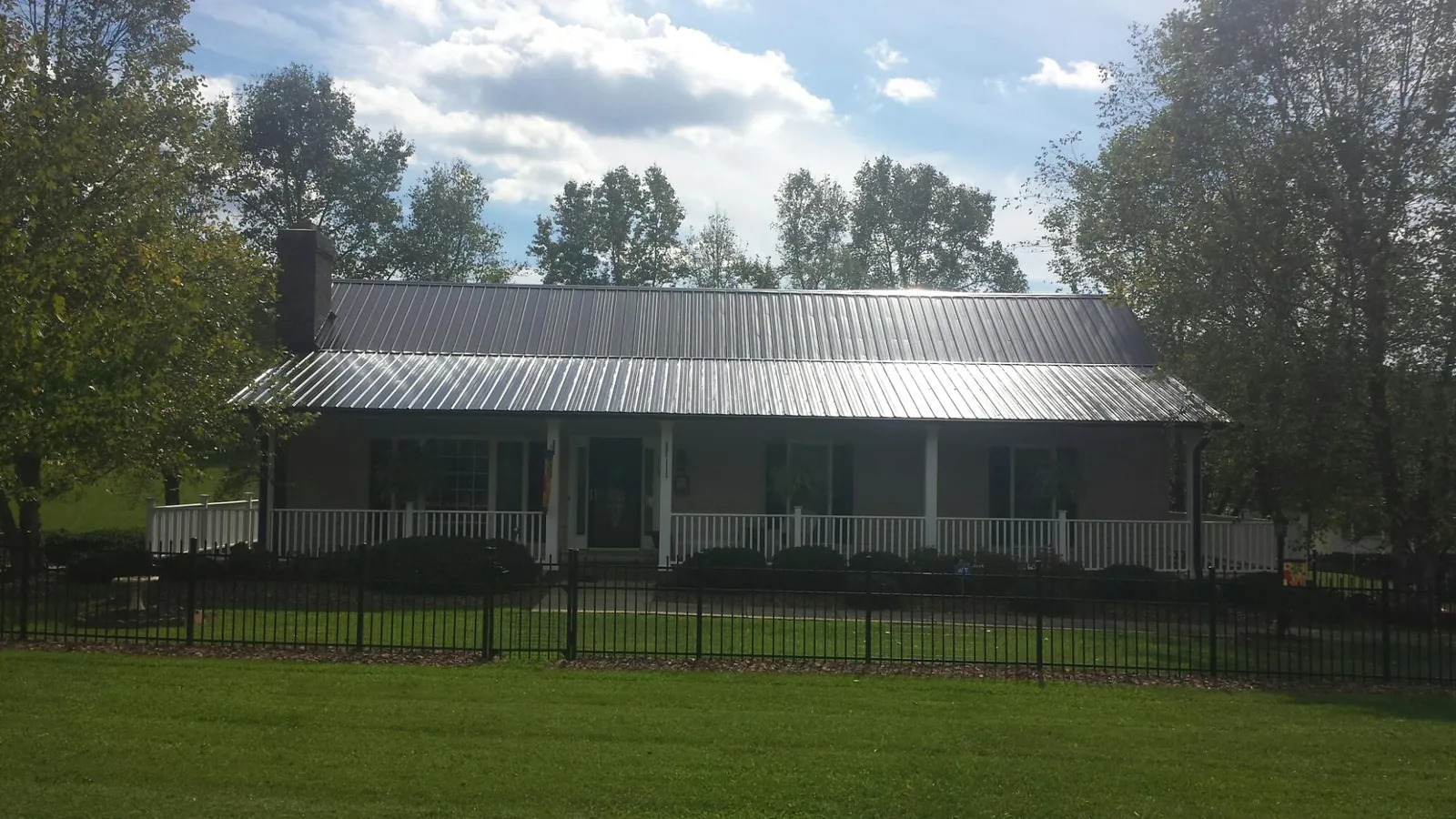 Gray metal roof on a brick ranch with a full width front porch — Gutter Guard Installation work by our crew in Watertown